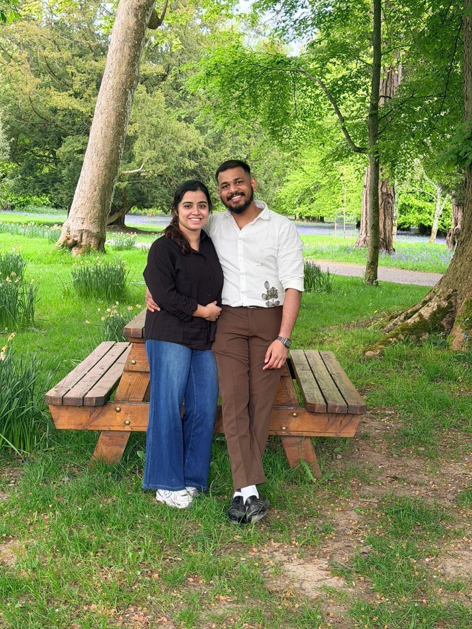 Leyo and Anju standing together among trees and bluebells.