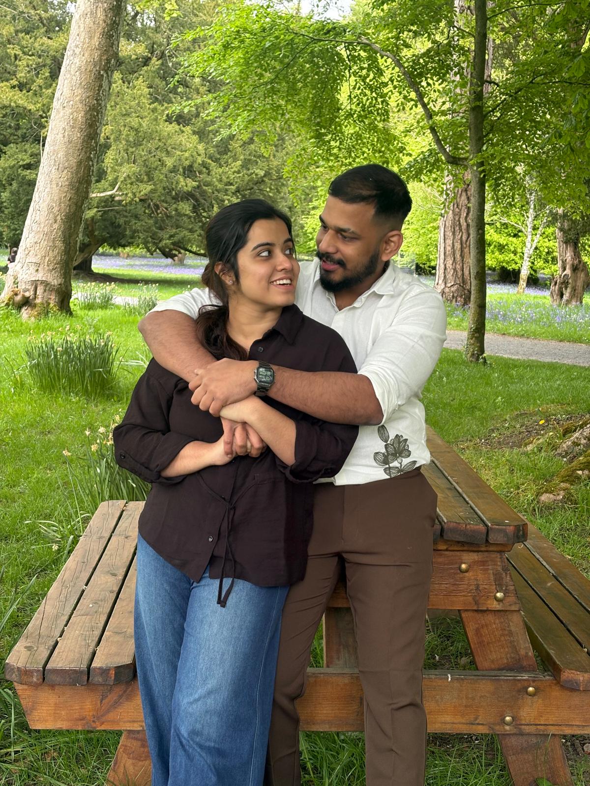 Leyo and Anju sharing a smile beneath the garden trees.