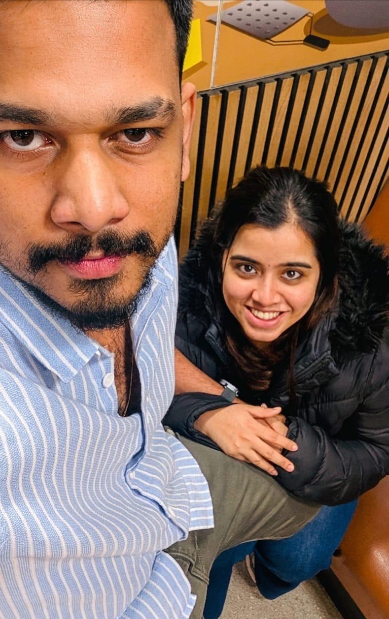 A close-up selfie of Leyo and Anju sitting together indoors.